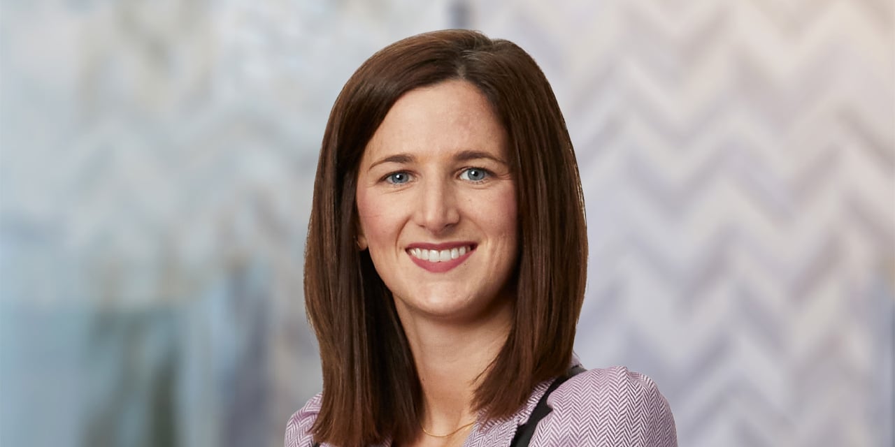 Professional headshot of Anne Sample on an abstract background.