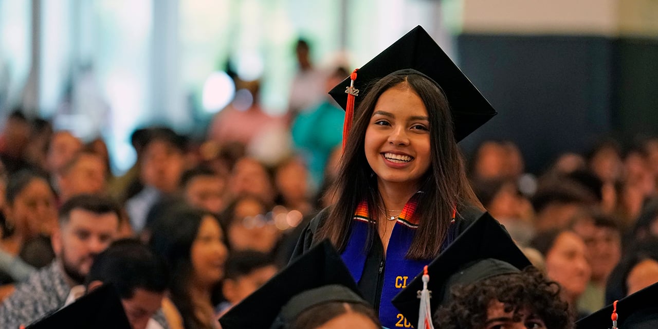 Graduate wearing cap and gown standing in graduation venue