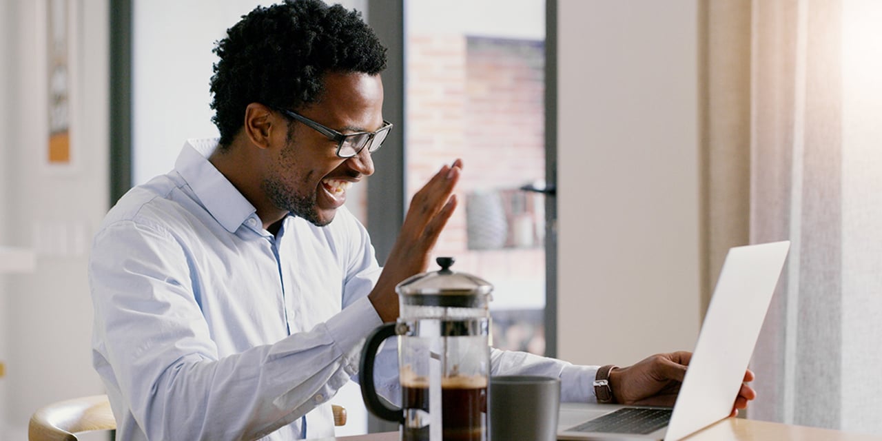 Man waving at a laptop screen.